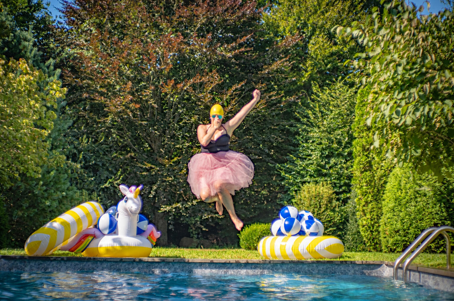 Tracy Weiss leaping into a pool in a pink tutu and yellow swim cap